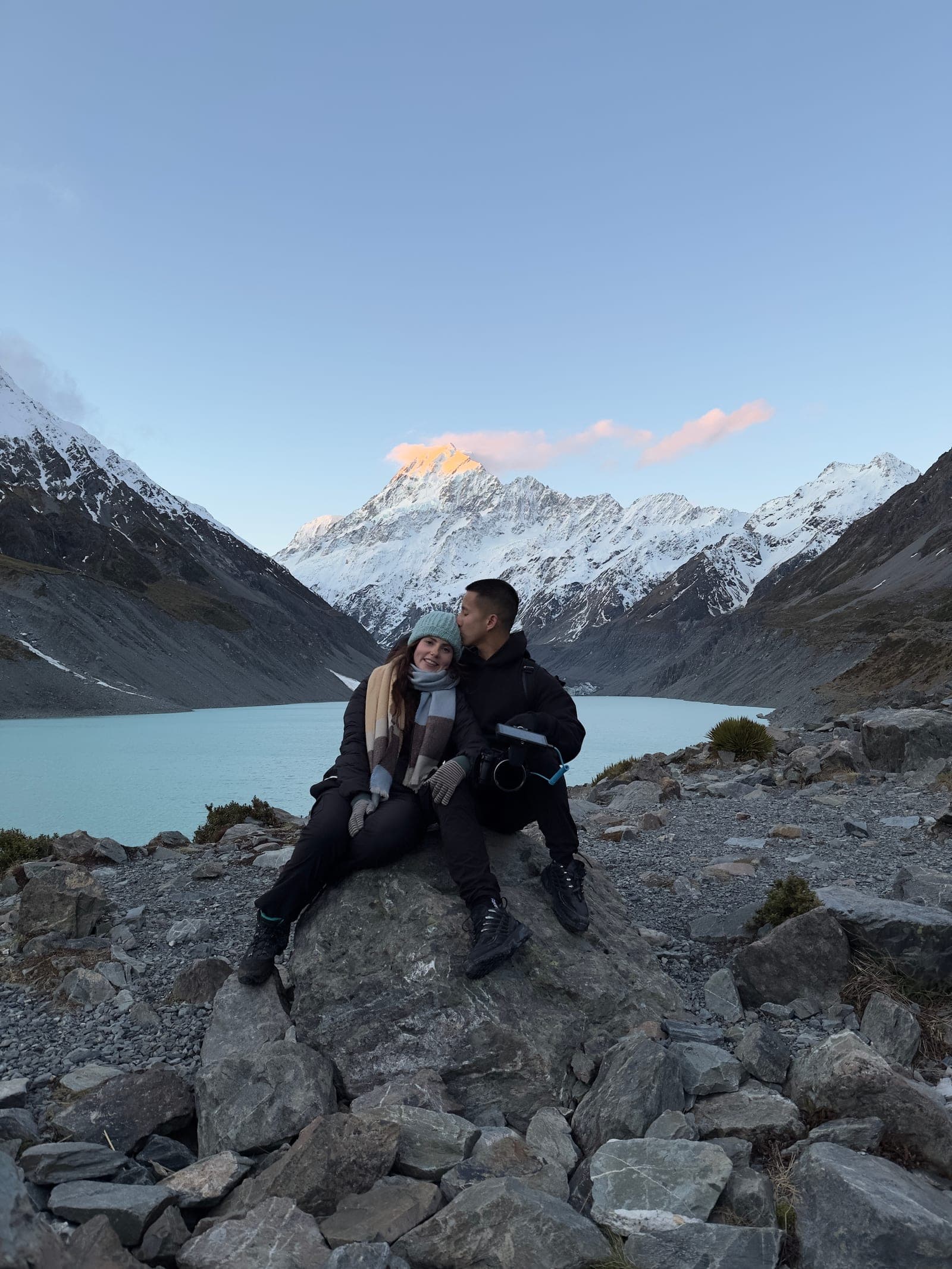 Claire and Martin sitting on the rocks by a glacial lake beneath Aoraki / Mount Cook